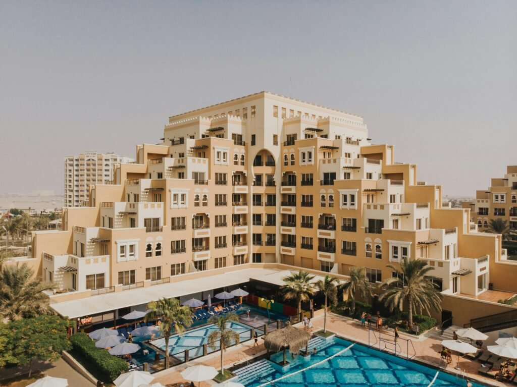 Aerial view of a modern architectural building in Dubai with a swimming pool in the foreground.